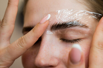 The master uses a plastic film during lamination of the eyebrows.