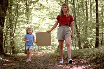 Little caucasian girl with mother holding poster protecting the planet