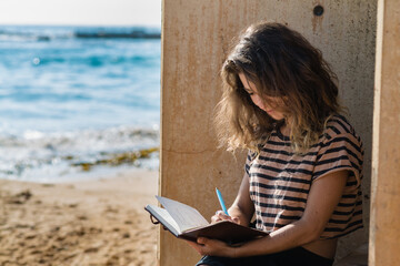 traveller writing in diary by the ocean