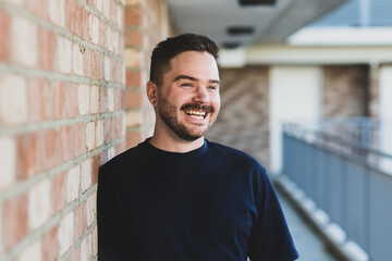 30 something man leaning against brick wall