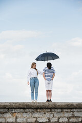 Girl covering sad boy with umbrella with copy space. Depression, sadness and mourning concept....