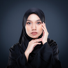 Close up portrait of a beautiful female model wearing traditional dress and hijab, a lifestyle apparel for Muslim women isolated on grey background. Idul Fitri and hijab fashion concept.