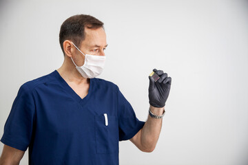 doctor in blue form, black gloves and white mask holds stained histology slide which is ready for...