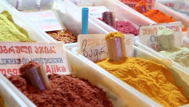 Assortment of colorful caucasus spices at oriental bazaar, 4k video. Name of spices writes in English, Georgian and Russian letters.