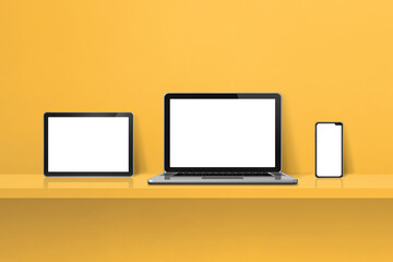 Laptop, mobile phone and digital tablet pc on yellow wall shelf. Horizontal background