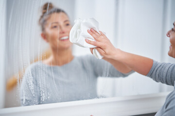 Picture of yound woman cleaning mirror window