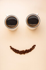 Smile face made from two cups of coffee and coffee beans. Cute, fun coffee mockup. Morning positive coffee concept