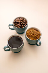 Coffee abstract, creative concept. Coffee beans, roasted soluble coffee and cuffee drink in cups. Three types of coffee.