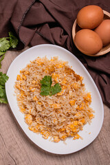 Thai food egg fried rice in white plate on wooden floor