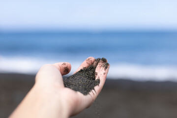 Female hands with black sand. Summer holidays and vacation concept. Close up. Selective focus