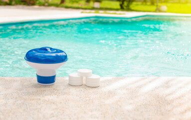 Pool float and chlorine tablets, Close up of a float and chlorine tablets on the edge of a swimming pool. Tablets with chlorine dispenser for swimming pool. Chlorine tablets with dosing float
