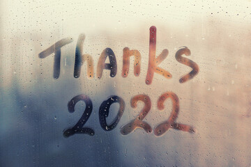 lettering Thanks and numbers 2022 paint with finger with streaks of water on splashed by rain foggy...