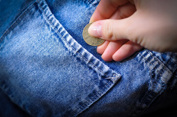 hand puts gold coin change in jeans pocket .Savings concept 