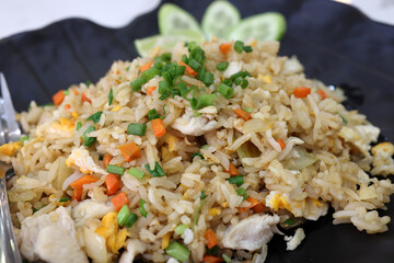 Thai style chicken fried rice cucumber slices on dark plate