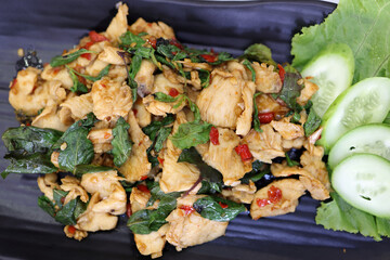 Thai style stair fried basil chicken on dark plate