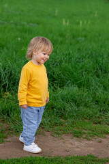 Portrait of little boy in yellow overalls in park