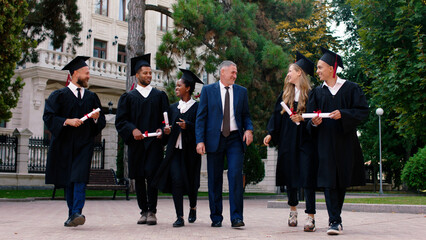 Walking in front of the camera graduates students multiracial and their professor charismatic man...