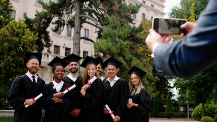 In a perfect day group of multiracial graduates young students in a graduation caps doing some...