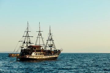 Fototapeta na wymiar Tourists sailing on old pirate boat. Old ship is sailing on the sea.