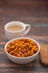 Close-Up of crunchy Indian mixture snacks with hot tea or Coffee time and handmade cookies (biscuits). Studio shoot at declined angle.