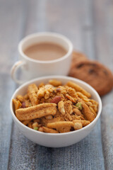 Close-Up of crunchy Indian mixture snacks with hot tea or Coffee time and handmade cookies (biscuits). Studio shoot at declined angle.