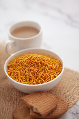 Close-Up of crunchy Indian mixture snacks with hot tea or Coffee time and handmade cookies (biscuits). Studio shoot at declined angle.