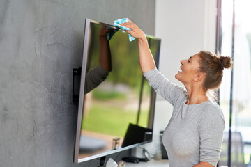 Picture of young woman cleaning tv screen