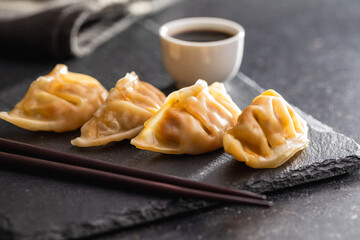 Chinese dumplings abd soy sauce on cutting board.