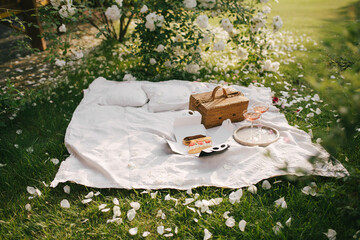 Beautiful picnic with fresh sweet eclairs and two glasses of rose champagne in blooming garden.