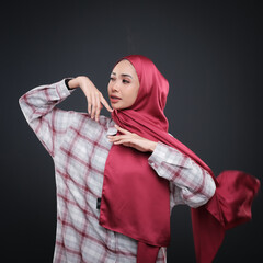 Half height portrait of a beautiful female model wearing traditional dress and hijab, a lifestyle apparel for Muslim women isolated on grey background. Idul Fitri and hijab fashion concept.
