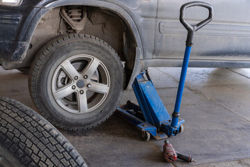 Fototapeta premium Jacking up a car to change a tyre after a roadside puncture with the jack inserted under the bodywork raising the vehicle. Replacing wheels on a car. Car service.