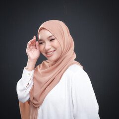 Half height portrait of a beautiful female model wearing traditional dress and hijab, a lifestyle apparel for Muslim women isolated on grey background. Idul Fitri and hijab fashion concept.