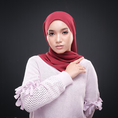 Half height portrait of a beautiful female model wearing traditional dress and hijab, a lifestyle apparel for Muslim women isolated on grey background. Idul Fitri and hijab fashion concept.