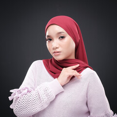 Half height portrait of a beautiful female model wearing traditional dress and hijab, a lifestyle apparel for Muslim women isolated on grey background. Idul Fitri and hijab fashion concept.