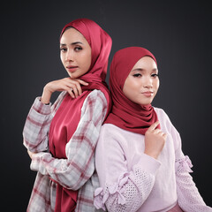 Half height portrait of a beautiful female model wearing traditional dress and hijab, a lifestyle apparel for Muslim women isolated on grey background. Idul Fitri and hijab fashion concept.