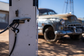 A gas pump with an old American truck in the background