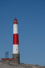 Fototapeta na wymiar A white and red lighthouse in front of a blue sky at Diaz Point near Lüderitz in Namibia
