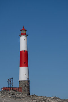 A white and red lighthouse in front of a blue sky at Diaz Point near Lüderitz in Namibia