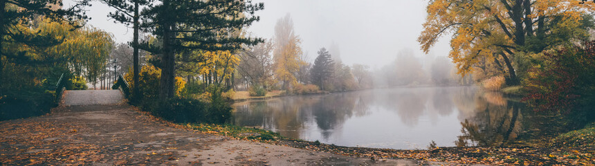 Picturesque panorama of Autumn landscape in park. Foggy sunrise in Vienna Austria park