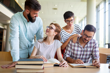 Happy university students studying with books in library. Group of multiracial people in college