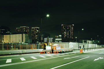 深夜の道路の工事現場で交通整理の仕事をする警備員の風景