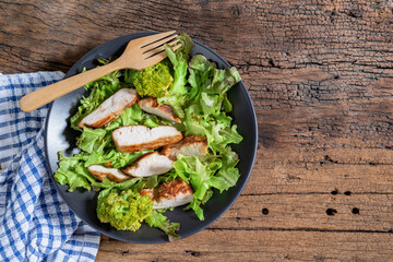 Healthy food salad bowl has chicken carrot broccoli on wood table.