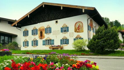 Fototapeta na wymiar schön bemaltes Gästehaus in Bad Kohlgrub mit Blumenschmuck unter blauem Himmel