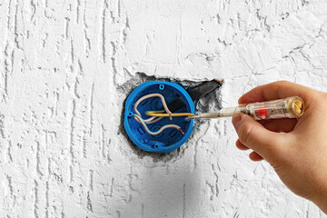 electrician looking for a phase wire in electrical wiring using an indicator screwdriver