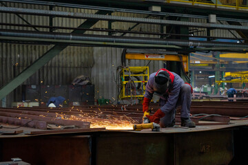 Welder welding a steel plate on a workshop of blocks