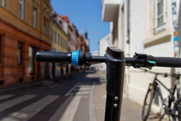 Handlebars of an e-scooter looking down a street in a downtown area.