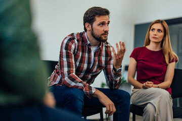 Focus on the bearded man talking about himself and his mental problems during group therapy.