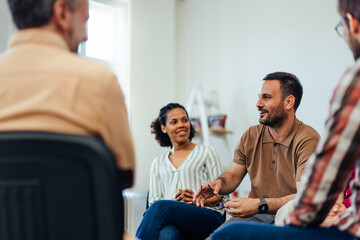 Focus on the casually dressed man, talking about his mental health during the group therapy.