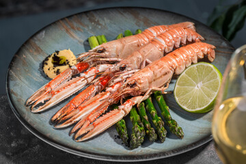 three cooked king prawns on a plate with asparagus and lime 