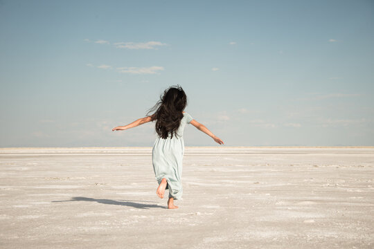 woman in blue dress running on white salt flats in vast landscape of Utah